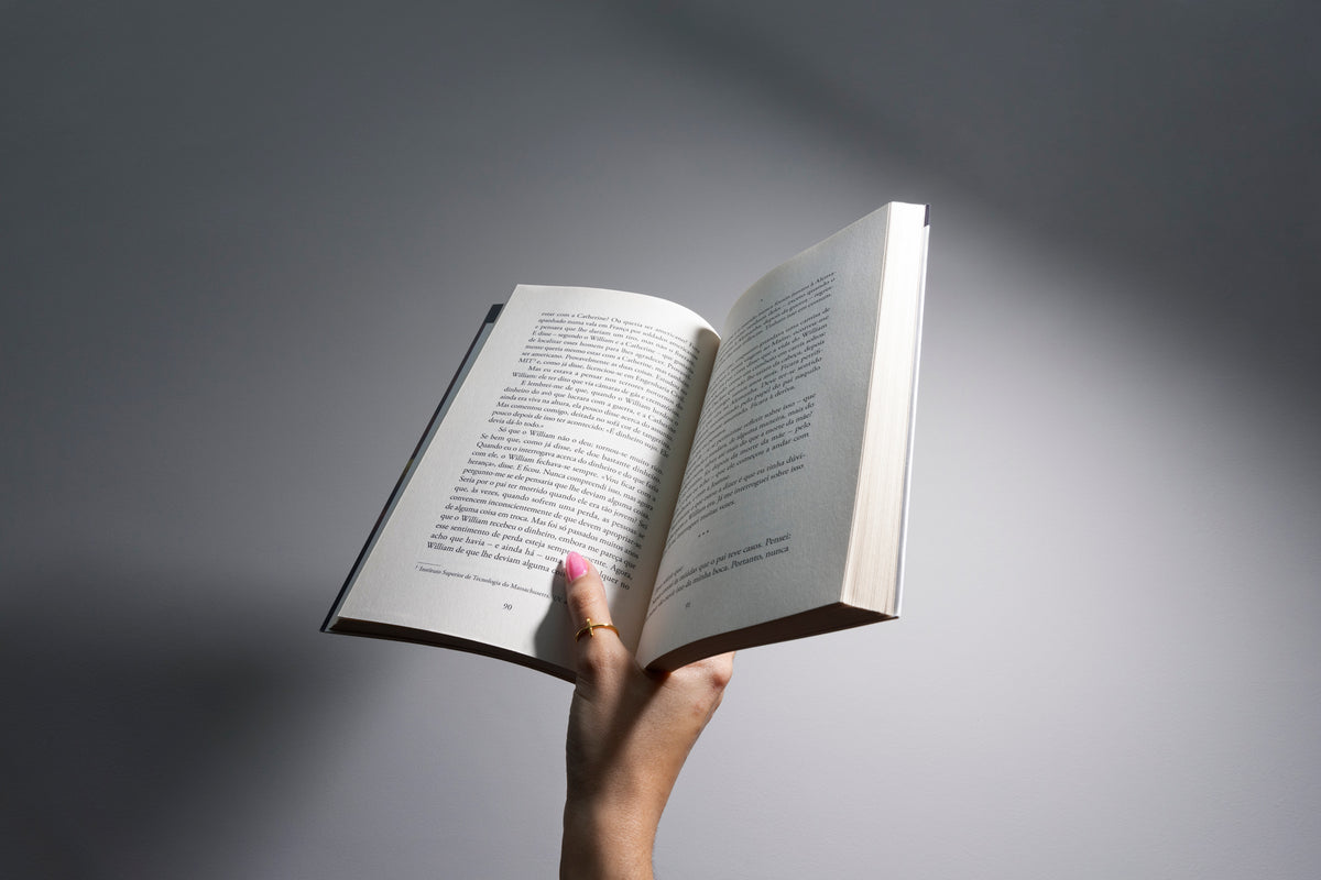 Hand holding an open book, perfect for summer beach reading books.