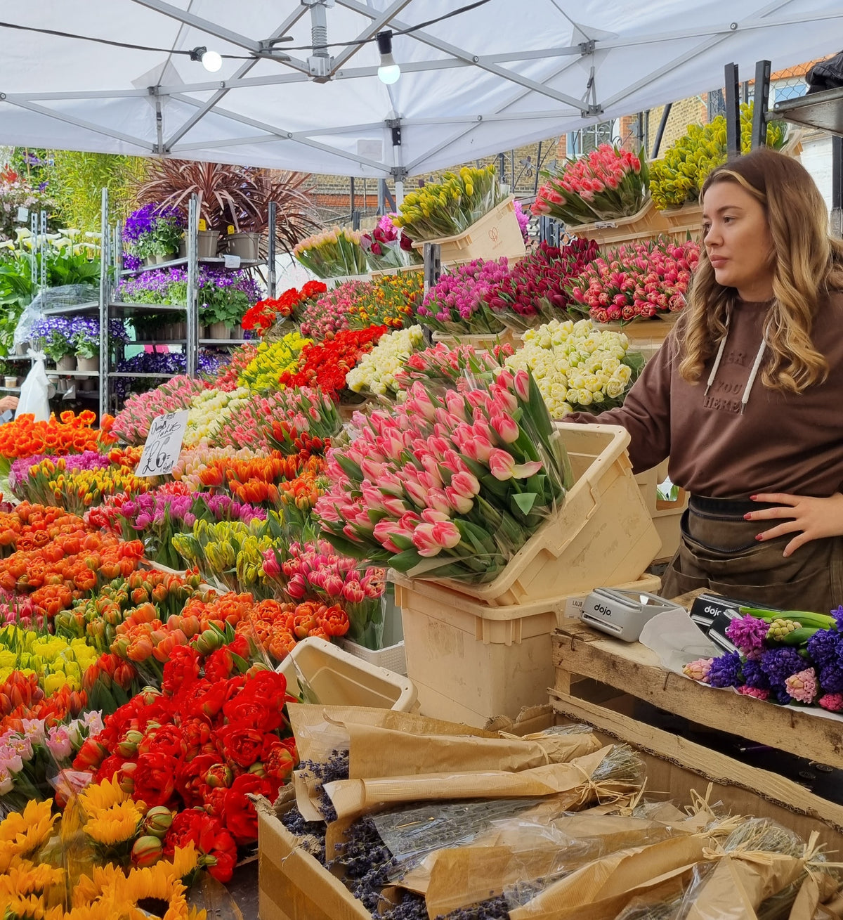 exploring east london neighborhoods with vibrant flower market and vendor surrounded by colorful blooms