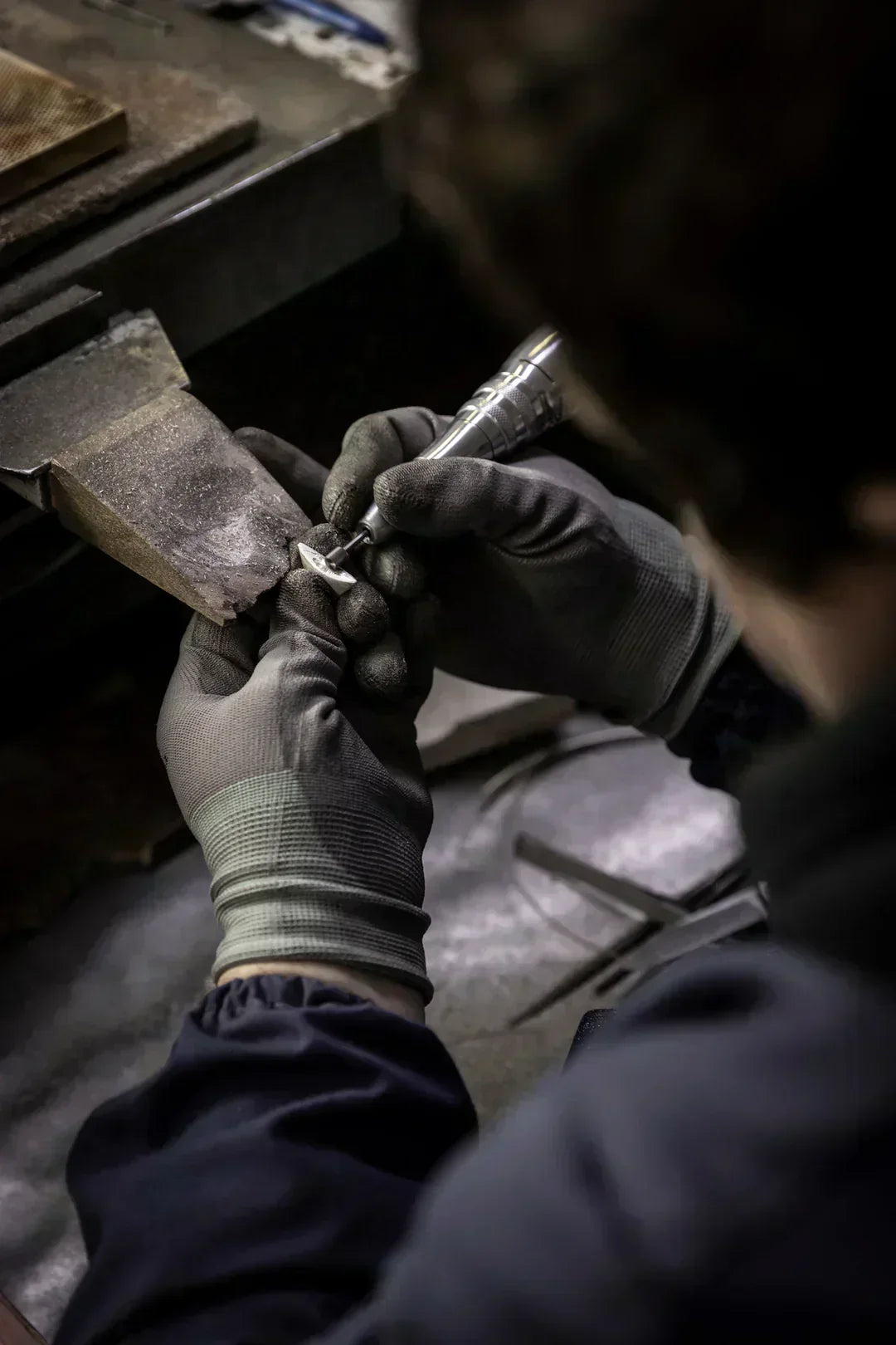 Craftsman creating 925 sterling silver jewelry investment in Europe with precision tools in a workshop.