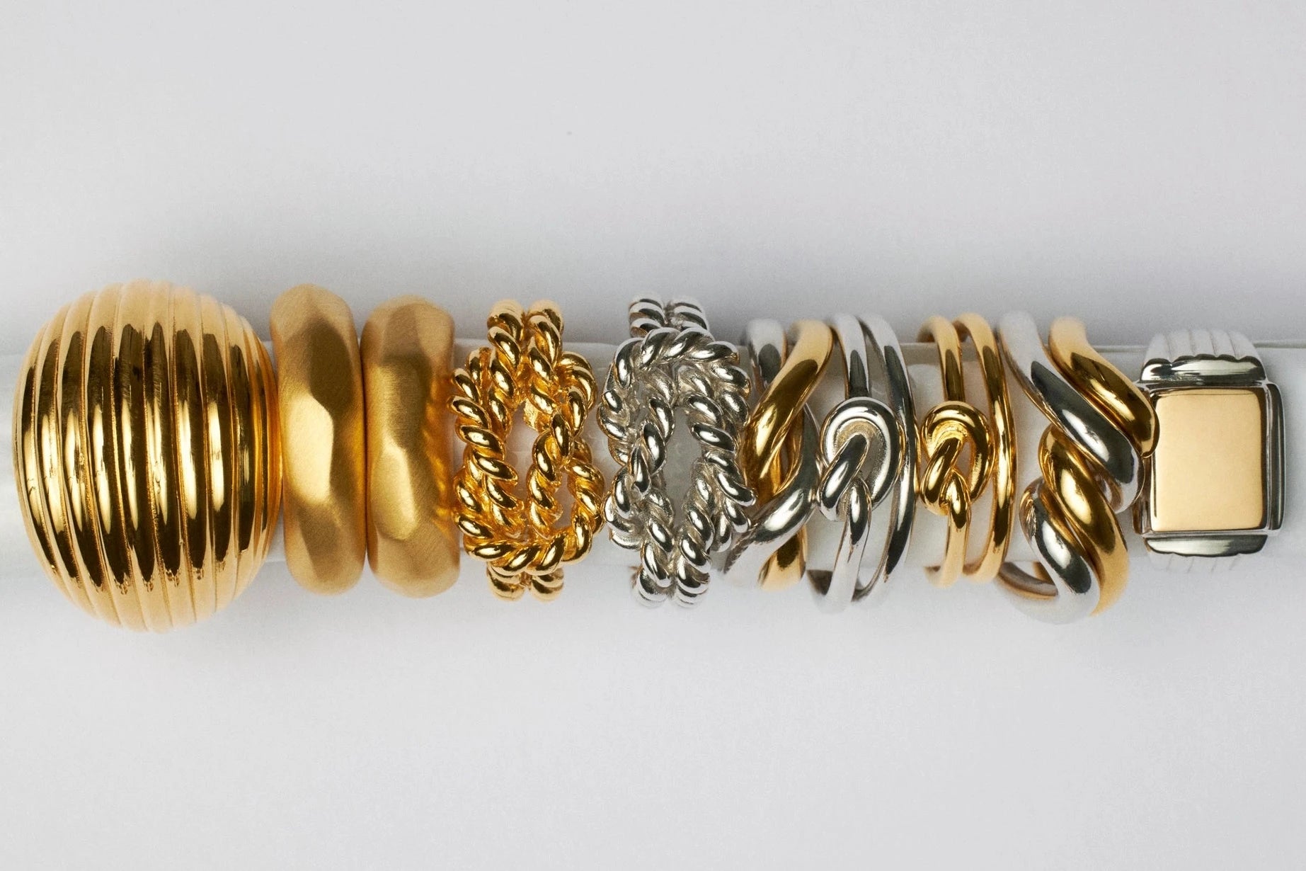Gold and silver bracelet with various links on a white background