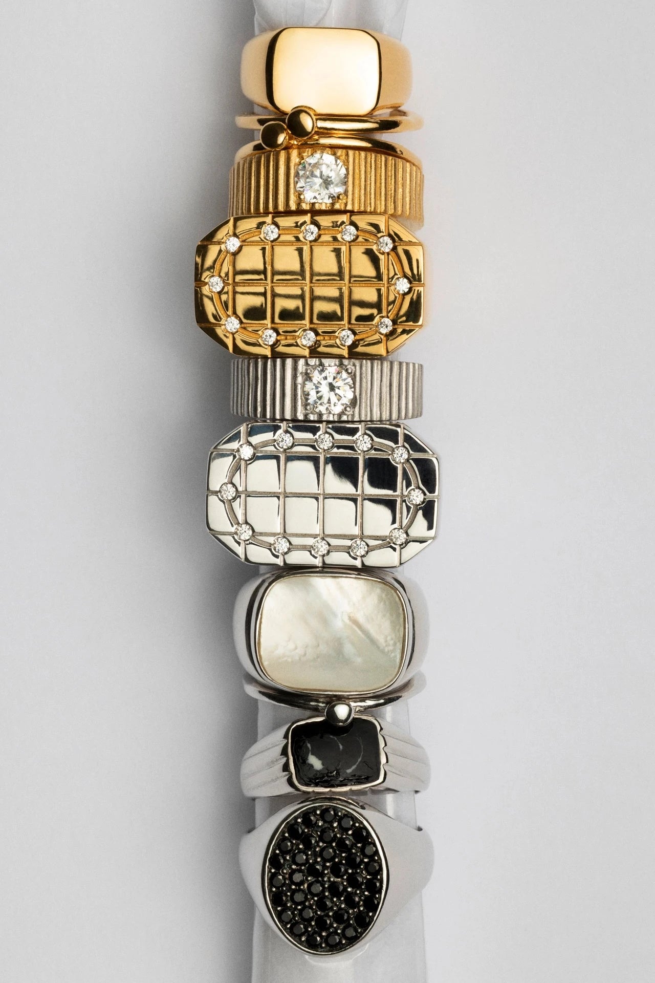 Stack of gold and silver bracelets on a white background