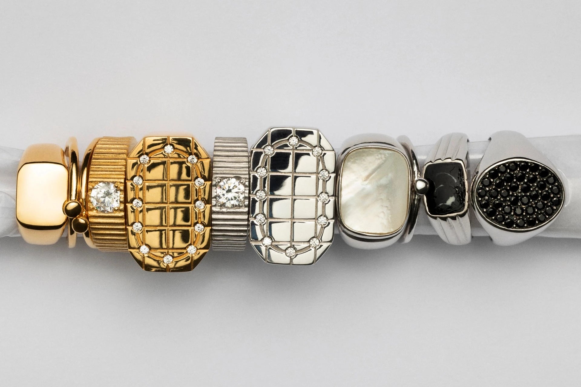 Stack of gold and silver bracelets on a white background