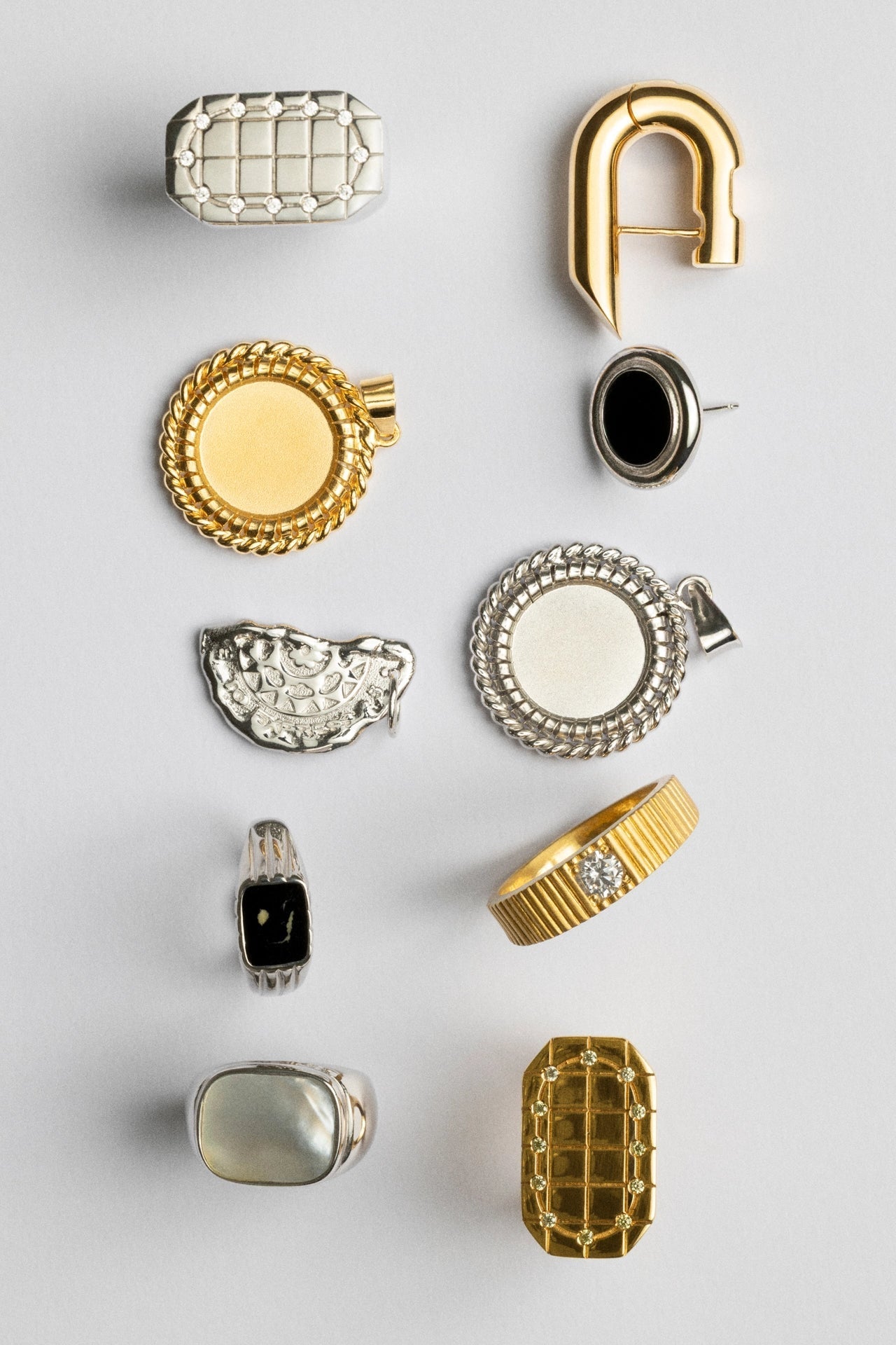 Collection of various jewelry pieces including rings and earrings on a light gray background CINCO gold earrings and necklaces from archive collection